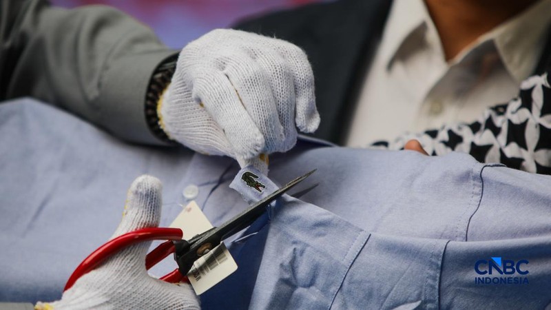 Petugas Direktorat Jenderal Kekayaan Intelektual (DJKI) menata produk menggunakan merek Lacoste tanpa hak saat konferensi pers di Jakarta, Senin (22/6/2026).