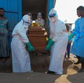 Petugas kesehatan dengan alat pelindung diri (APD) membawa peti mati korban yang diduga terinfeksi Ebola dari sebuah bangunan yang digunakan sebagai kamar mayat saat mereka mempersiapkan pemakaman di Pemakaman Nyamurongo, satu bulan setelah wabah din