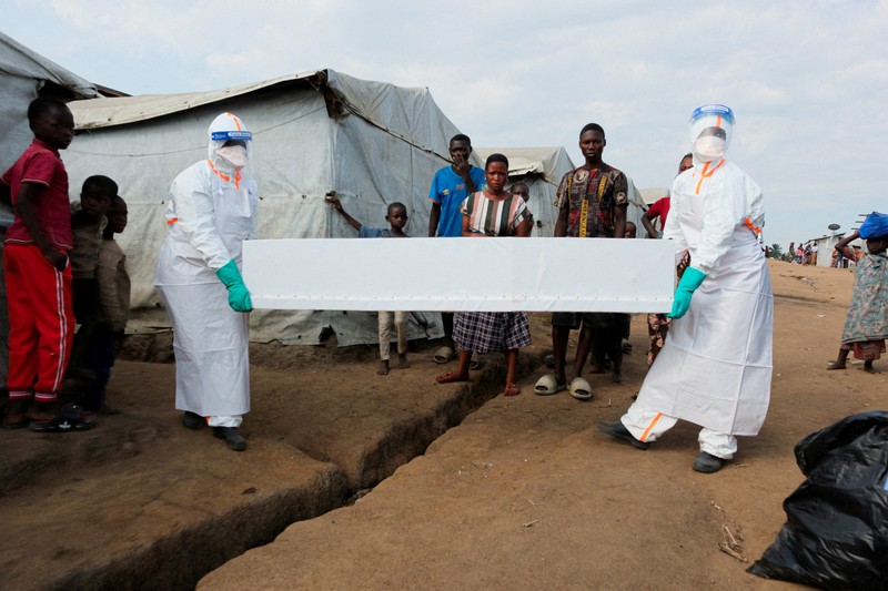 Petugas kesehatan dengan alat pelindung diri (APD) membawa peti mati korban yang diduga terinfeksi Ebola dari sebuah bangunan yang digunakan sebagai kamar mayat saat mereka mempersiapkan pemakaman di Pemakaman Nyamurongo, satu bulan setelah wabah dinyatakan, di Bunia, bagian timur Republik Demokratik Kongo, 18 Juni 2026. (REUTERS/Gradel Muyisa Mumbere)