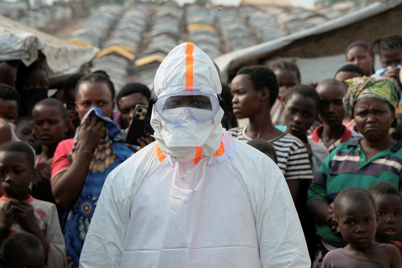 Petugas kesehatan dengan alat pelindung diri (APD) membawa peti mati korban yang diduga terinfeksi Ebola dari sebuah bangunan yang digunakan sebagai kamar mayat saat mereka mempersiapkan pemakaman di Pemakaman Nyamurongo, satu bulan setelah wabah dinyatakan, di Bunia, bagian timur Republik Demokratik Kongo, 18 Juni 2026. (REUTERS/Gradel Muyisa Mumbere)