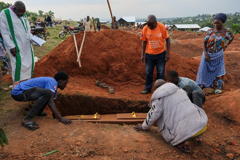 Petugas kesehatan dengan alat pelindung diri (APD) membawa peti mati korban yang diduga terinfeksi Ebola dari sebuah bangunan yang digunakan sebagai kamar mayat saat mereka mempersiapkan pemakaman di Pemakaman Nyamurongo, satu bulan setelah wabah dinyatakan, di Bunia, bagian timur Republik Demokratik Kongo, 18 Juni 2026. (REUTERS/Gradel Muyisa Mumbere)
