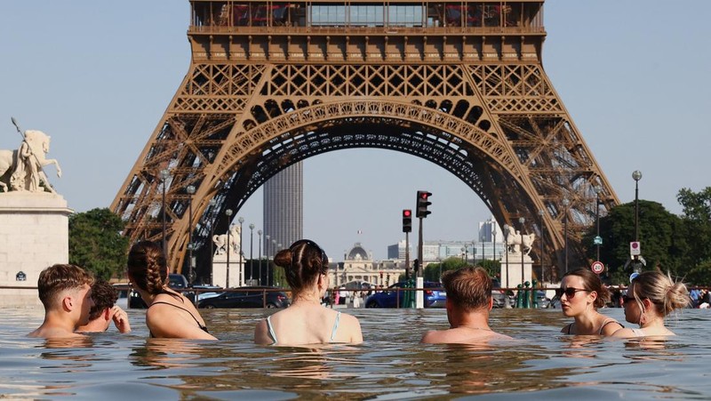 Orang-orang mendinginkan diri di Air Mancur Trocadero di sebelah Menara Eiffel saat suhu meningkat selama gelombang panas yang melanda sebagian besar negara, di Paris, Prancis, 22 Juni 2026.