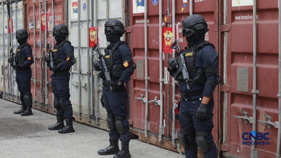 Sejumlah petugas bersenjata berjaga di depan kontainer saat Penindakan Bea Cukai Berupa Peti Kemas berisi pakaian bekas di Buffer Area TPS CDC Banda, Jalan Banda No.1, Tanjung Priok, Kota Jakarta Utara, Selasa, (23/6/2026). (CNBC Indonesia/Muhammad S