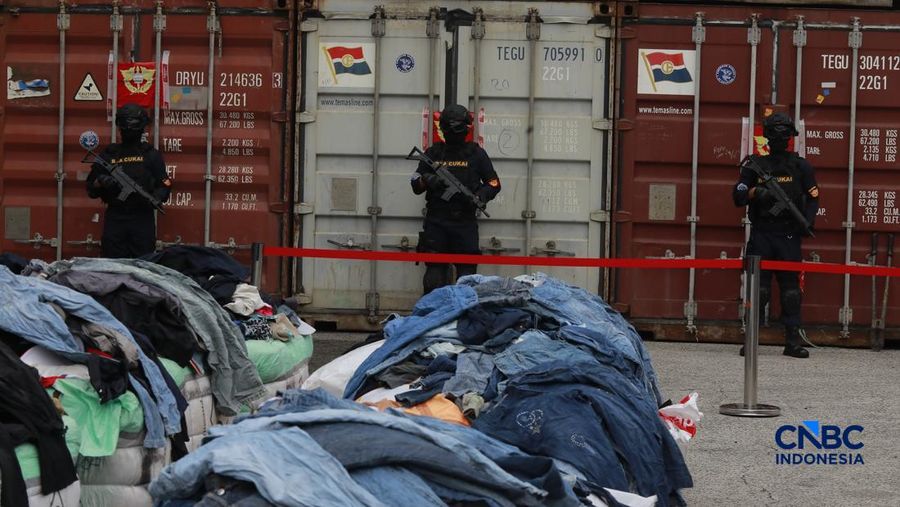 Sejumlah petugas bersenjata berjaga di depan kontainer saat Penindakan Bea Cukai Berupa Peti Kemas berisi pakaian bekas di Buffer Area TPS CDC Banda, Jalan Banda No.1, Tanjung Priok, Kota Jakarta Utara, Selasa, (23/6/2026). (CNBC Indonesia/Muhammad S