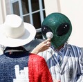 Seseorang yang mengenakan topeng alien duduk di antara penonton dengan kipas angin listrik portabel selama peragaan koleksi busana pria Musim Semi/Musim Panas 2027 karya Thom Browne sebagai bagian dari Milan Fashion Week, di Milan, Italia, 22 Juni 20
