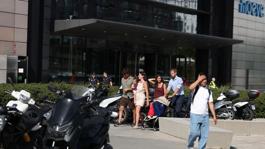 Orang-orang berjalan di dekat gedung pencakar langit yang menjadi kantor perusahaan minyak Spanyol, Movie, yang dievakuasi karena kebakaran, di Madrid, Spanyol, 23 Juni 2026.