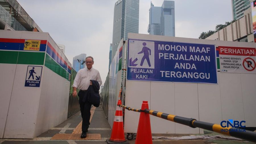 Warga berjalan kaki melewati trotoar darurat yang didekorasi menyerupai lorong taman labirin di atas kawasan proyek pengembangan kawasan Stasiun MRT Bundaran Hotel Indonesia, Jakarta, Rabu (24/6/2026).