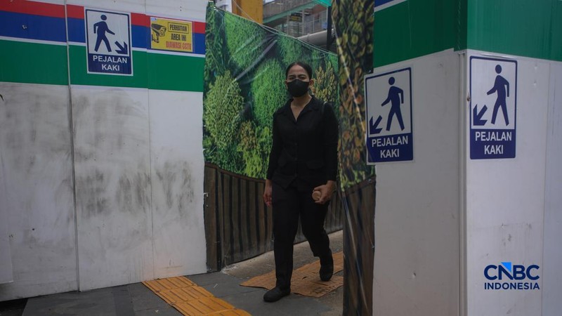 Warga berjalan kaki melewati trotoar darurat yang didekorasi menyerupai lorong taman labirin di atas kawasan proyek pengembangan kawasan Stasiun MRT Bundaran Hotel Indonesia, Jakarta, Rabu (24/6/2026).