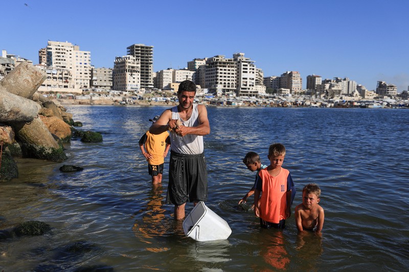 Warga Palestina memadati Pantai Kota Gaza pada Minggu (21/6/2026) untuk menyegarkan diri di tengah musim panas yang menyengat. (REUTERS/DAWOUD ABU ALKAS)