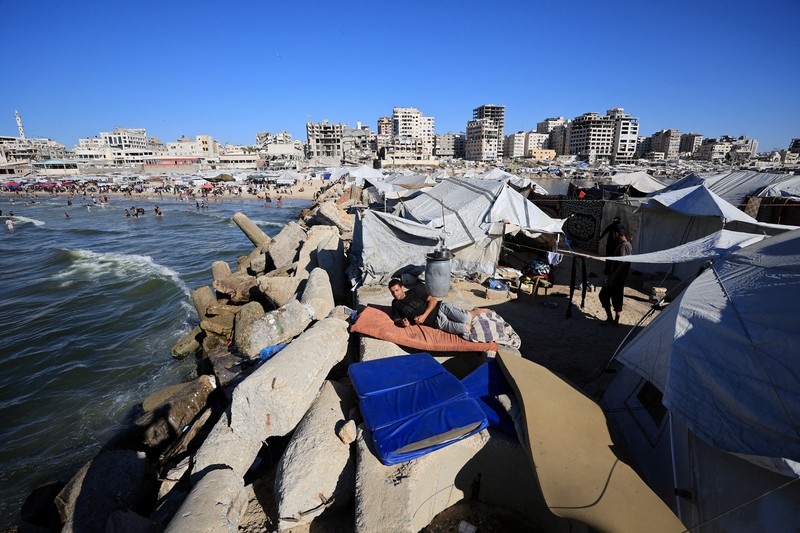 Warga Palestina memadati Pantai Kota Gaza pada Minggu (21/6/2026) untuk menyegarkan diri di tengah musim panas yang menyengat. (REUTERS/DAWOUD ABU ALKAS)