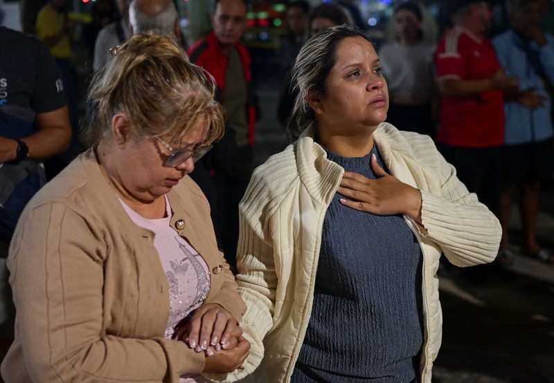 Fanny Nasri menunggu di lokasi bangunan yang runtuh sementara petugas penyelamat mencari putranya, Antonio Nasri, bersama Noemi Cordoba, yang menunggu kabar tentang cucunya, setelah gempa bumi di Caracas, Venezuela, 25 Juni 2026. (REUTERS/Gaby Oraa)