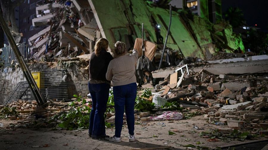 Fanny Nasri menunggu di lokasi bangunan yang runtuh sementara petugas penyelamat mencari putranya, Antonio Nasri, bersama Noemi Cordoba, yang menunggu kabar tentang cucunya, setelah gempa bumi di Caracas, Venezuela, 25 Juni 2026. (REUTERS/Gaby Oraa)