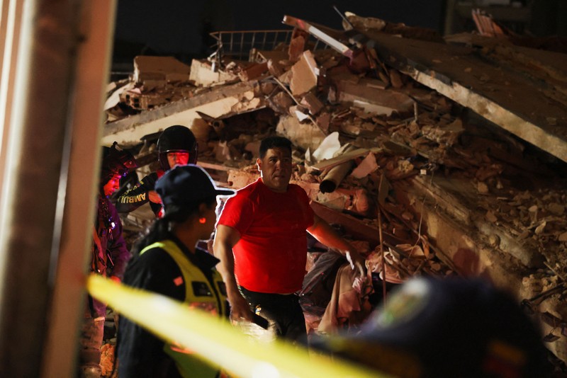 Fanny Nasri menunggu di lokasi bangunan yang runtuh sementara petugas penyelamat mencari putranya, Antonio Nasri, bersama Noemi Cordoba, yang menunggu kabar tentang cucunya, setelah gempa bumi di Caracas, Venezuela, 25 Juni 2026. (REUTERS/Gaby Oraa)