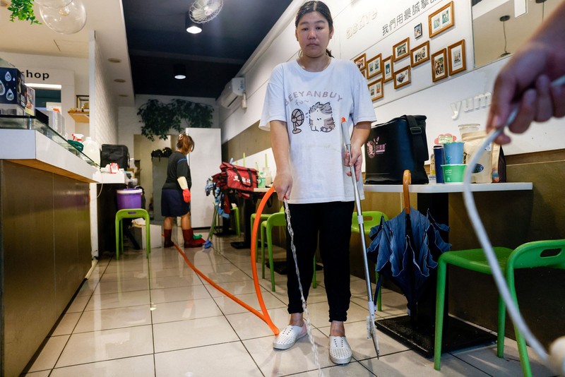 Warga membersihkan lumpur dan puing-puing dari daerah yang tergenang banjir setelah hujan deras akibat Badai Tropis Mekkhala di Hsinchu, Taiwan, 26 Juni 2026. (REUTERS/Ann Wang)