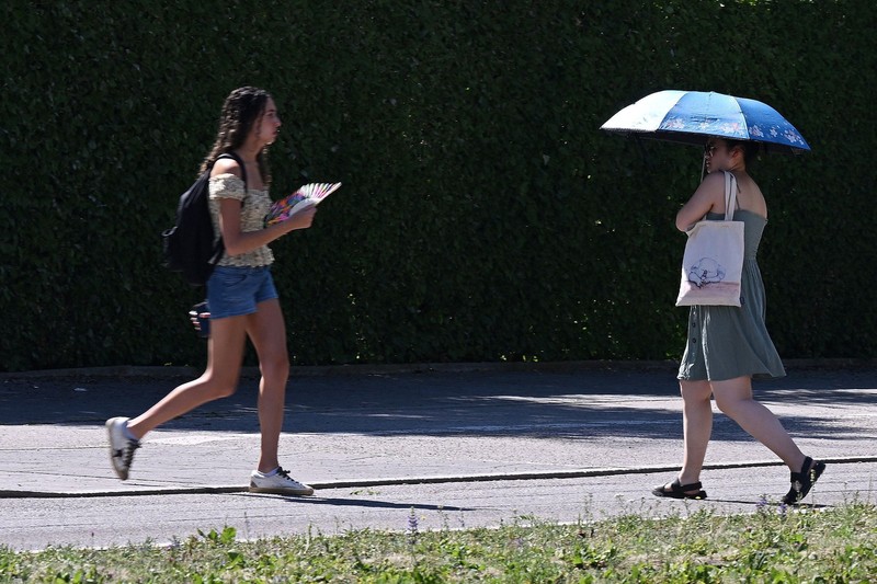 Orang-orang menggunakan payung dan kipas angin untuk melindungi diri dari suhu tinggi di Munich, Jerman, 26 Juni 2026. (REUTERS/Angelika Warmuth)