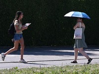 Orang-orang menggunakan payung dan kipas angin untuk melindungi diri dari suhu tinggi di Munich, Jerman, 26 Juni 2026. (REUTERS/Angelika Warmuth)