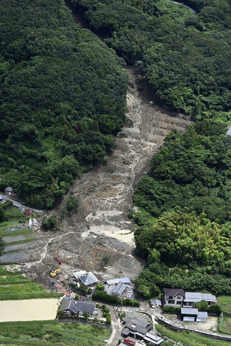 Petugas polisi dan tim penyelamat melakukan operasi pencarian dan penyelamatan di sebuah rumah yang tertimbun tanah longsor akibat hujan lebat di Hirao, Prefektur Yamaguchi, Jepang, Sabtu (27/6/2026). (Kyodo/via REUTERS)