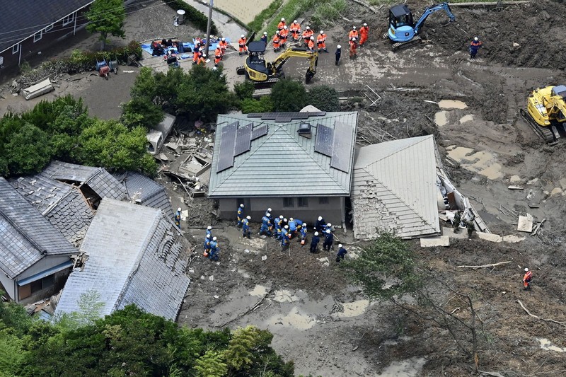 Petugas polisi dan tim penyelamat melakukan operasi pencarian dan penyelamatan di sebuah rumah yang tertimbun tanah longsor akibat hujan lebat di Hirao, Prefektur Yamaguchi, Jepang, Sabtu (27/6/2026). (Kyodo/via REUTERS)