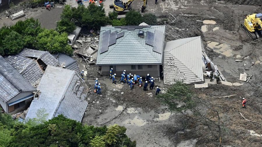 Petugas polisi dan tim penyelamat melakukan operasi pencarian dan penyelamatan di sebuah rumah yang tertimbun tanah longsor akibat hujan lebat di Hirao, Prefektur Yamaguchi, Jepang, Sabtu (27/6/2026). (Kyodo/via REUTERS)