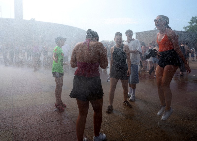 Orang-orang menikmati semprotan air dari meriam air polisi di depan stadion Olimpiade Olympiastadion selama gelombang panas yang sedang berlangsung di Berlin, Jerman, 28 Juni 2026. (REUTERS/Maryam Majd)