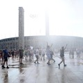 Orang-orang menikmati semprotan air dari meriam air polisi di depan stadion Olimpiade Olympiastadion selama gelombang panas yang sedang berlangsung di Berlin, Jerman, 28 Juni 2026. (REUTERS/Maryam Majd)
