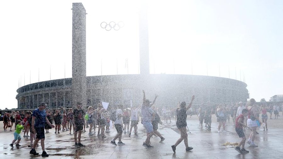 Orang-orang menikmati semprotan air dari meriam air polisi di depan stadion Olimpiade Olympiastadion selama gelombang panas yang sedang berlangsung di Berlin, Jerman, 28 Juni 2026. (REUTERS/Maryam Majd)