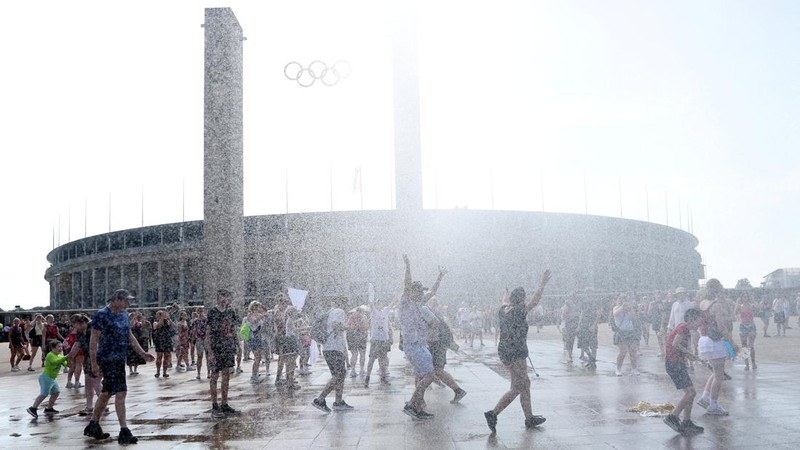 Orang-orang menikmati semprotan air dari meriam air polisi di depan stadion Olimpiade Olympiastadion selama gelombang panas yang sedang berlangsung di Berlin, Jerman, 28 Juni 2026. (REUTERS/Maryam Majd)