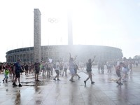 Orang-orang menikmati semprotan air dari meriam air polisi di depan stadion Olimpiade Olympiastadion selama gelombang panas yang sedang berlangsung di Berlin, Jerman, 28 Juni 2026. (REUTERS/Maryam Majd)