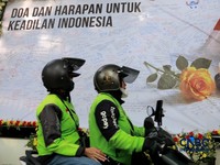 Pengemudi ojek online melintas di depan karangan bunga "Doa dan Harapan untuk Keadilan Indonesia" jelang sidang putusan terdakwa kasus dugaan korupsi pengadaan Chromebook dan Chrome Device Management (CDM) dalam program digitalisasi pendidikan di Kem