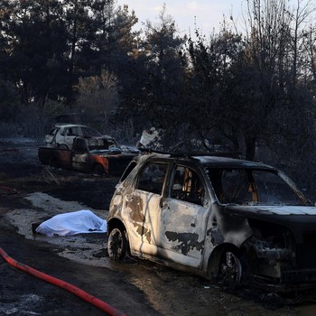 Jenazah korban kebakaran hutan tergeletak tertutup kain di samping mobil yang terbakar setelah kebakaran hutan di dekat desa Liti, Thessaloniki, Yunani, 30 Juni 2026. (REUTERS/Alexandros Avramidis)