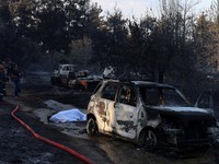 Jenazah korban kebakaran hutan tergeletak tertutup kain di samping mobil yang terbakar setelah kebakaran hutan di dekat desa Liti, Thessaloniki, Yunani, 30 Juni 2026. (REUTERS/Alexandros Avramidis)
