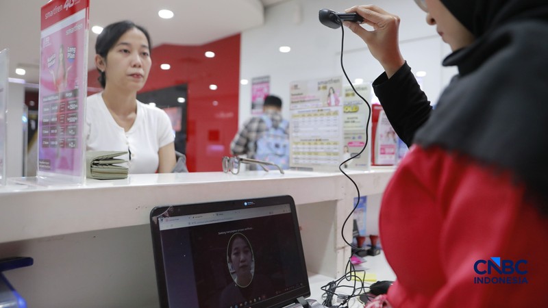 Seorang pengunjung melakukan sistem registrasi pelanggan layanan telekomunikasi berbasis data biometrik dengan dukungan teknologi pengenalan wajah di counter Smartfren, Mall Ambasador, Jakarta, Rabu, (1/7/2026). (CNBC Indonesia/Muhammad Sabki)