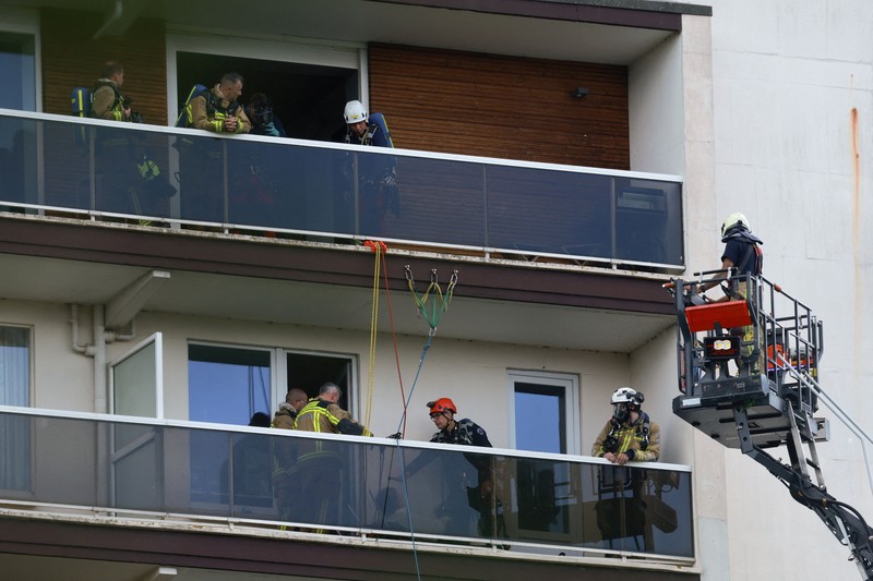 Para petugas penyelamat bekerja di lokasi kebakaran di sebuah gedung perumahan di Antwerp, Belgia, 1 Juli 2026. (REUTERS/Yves Herman)