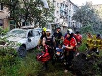 Para sukarelawan, paramedis, dan petugas penyelamat membawa seorang warga yang terluka di lokasi gedung apartemen yang rusak akibat serangan rudal dan pesawat tak berawak Rusia semalam, di tengah serangan Rusia terhadap Ukraina, di Kyiv, Ukraina, 2 J