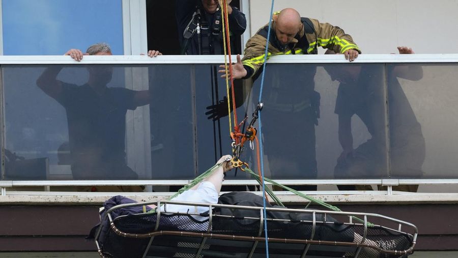 Tim penyelamat mengevakuasi seseorang di lokasi kebakaran di sebuah gedung perumahan di Antwerp, Belgia, 1 Juli 2026. (REUTERS/Yves Herman)