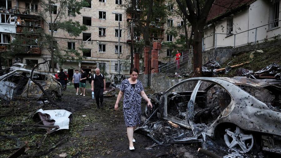 Warga berjalan melewati mobil-mobil yang hangus terbakar akibat serangan rudal dan pesawat tak berawak Rusia semalam, di tengah serangan Rusia terhadap Ukraina, di Kyiv, Ukraina, 2 Juli 2026.