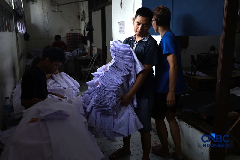 Pekerja menyelesaikan produksi pakain sekolah di konveksi rumahan kawasan Jakarta, Jumat (3/7/2026). (CNBC Indonesia/Tri Susilo)