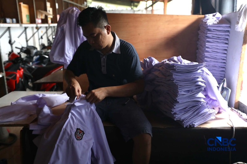 Pekerja menyelesaikan produksi pakain sekolah di konveksi rumahan kawasan Jakarta, Jumat (3/7/2026). (CNBC Indonesia/Tri Susilo)