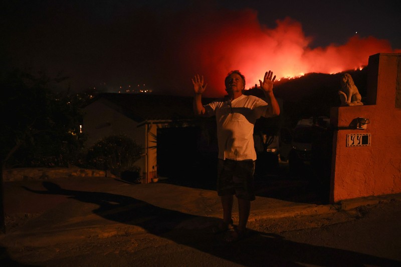 People look on as flames and smoke from a wildfire rise near Calonge, Spain, July 4, 2026. REUTERS/Bruna Casas     TPX IMAGES OF THE DAY