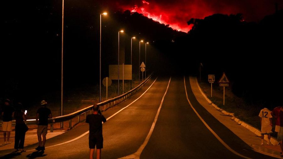 People look on as flames and smoke from a wildfire rise near Calonge, Spain, July 4, 2026. REUTERS/Bruna Casas     TPX IMAGES OF THE DAY