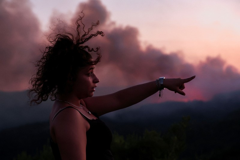 People look on as flames and smoke from a wildfire rise near Calonge, Spain, July 4, 2026. REUTERS/Bruna Casas     TPX IMAGES OF THE DAY