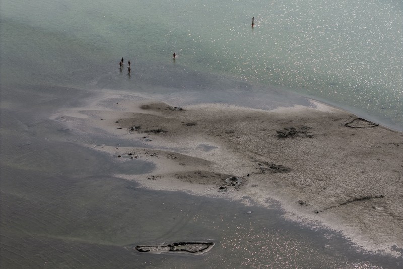 A drone view shows people walking on an exposed sandbank locally known as
