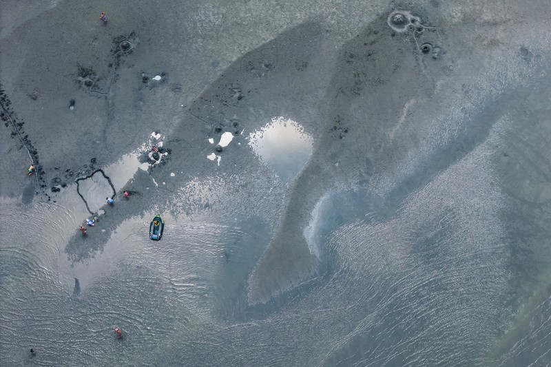 A drone view shows people walking on an exposed sandbank locally known as