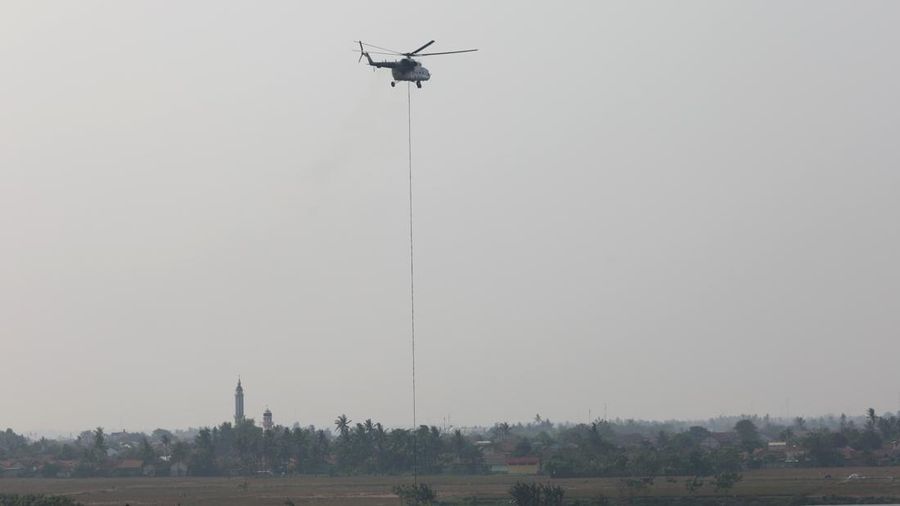 Helicopter water bombing mengisi ulang ember (bucket) di Danau Pulo yang berjarak sekitar 700 meter dari lokasi kebakaran TPA Jatiwaringin, Tangerang, Senin (6/7). (Dok BNPB)