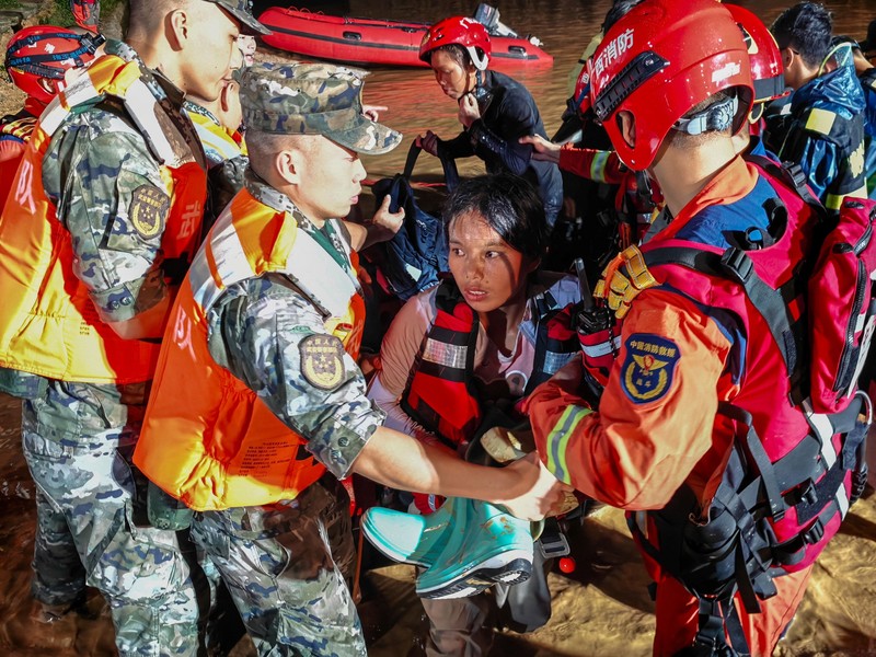Petugas polisi paramiliter mengevakuasi warga menggunakan perahu karet melalui daerah yang tergenang banjir setelah hujan deras akibat topan Maysak, di Nanning, Daerah Otonomi Guangxi Zhuang, Tiongkok, 6 Juli 2026. (cnsphoto via REUTERS)