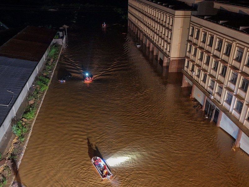 Petugas polisi paramiliter mengevakuasi warga menggunakan perahu karet melalui daerah yang tergenang banjir setelah hujan deras akibat topan Maysak, di Nanning, Daerah Otonomi Guangxi Zhuang, Tiongkok, 6 Juli 2026. (cnsphoto via REUTERS)