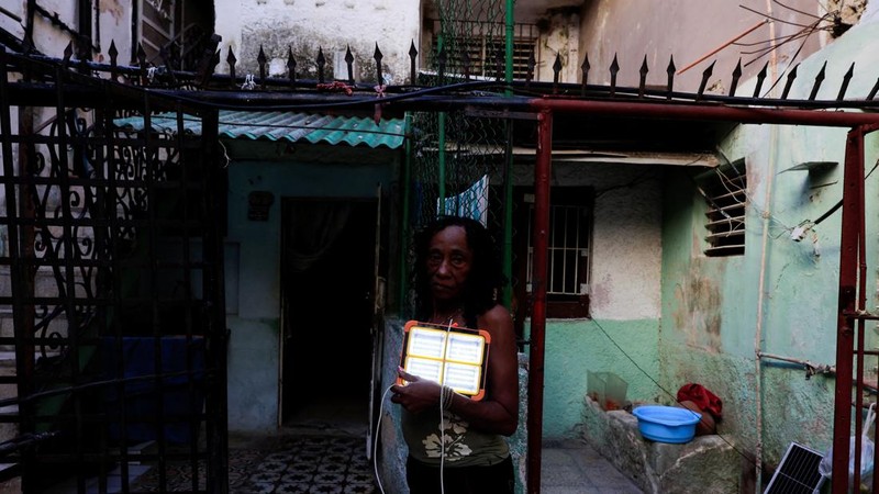 Josefina Rodriguez berpose untuk foto sambil memegang lampu isi ulangnya saat Kuba berjuang untuk memulihkan aliran listrik setelah runtuhnya jaringan listrik nasional sehari sebelumnya, yang menyebabkan jutaan orang masih tanpa listrik di seluruh negara kepulauan Karibia itu, di Havana, Kuba, 7 Juli 2026.