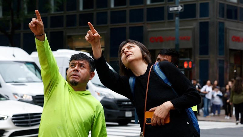 Orang-orang menunjuk ke atas di dekat sebuah bangunan di Jalan ke-42, yang dilaporkan memiliki masalah struktural, di Kota New York, AS, 7 Juli 2026.