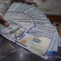 Petugas menjunjukkan uang pecahan dolar Amerika Serikat (AS) dan rupiah di Dolar Asia Money Changer, Jakarta, Rabu (8/7/2026). (CNBC Indonesia/Faisal Rahman)