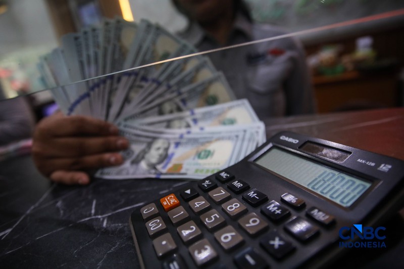 Petugas menjunjukkan uang pecahan dolar Amerika Serikat (AS) dan rupiah di Dolar Asia Money Changer, Jakarta, Rabu (8/7/2026). (CNBC Indonesia/Faisal Rahman)